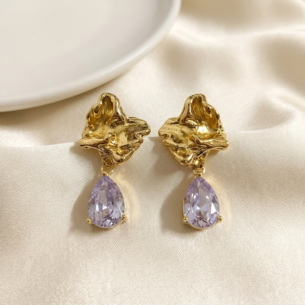 Woman wearing anti tarnish gold toned floral drop earrings with teardrop stone pendant by MahanandaFJ Atelier.