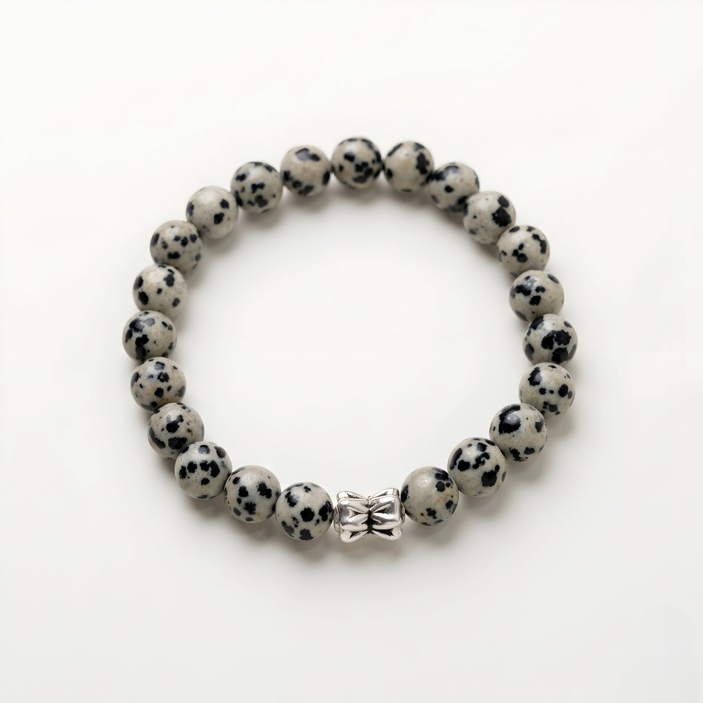 Natural Dalmatian Jasper bracelet featuring 8 mm cream and black speckled gemstone beads with a butterfly accent bead on a smooth stone background.