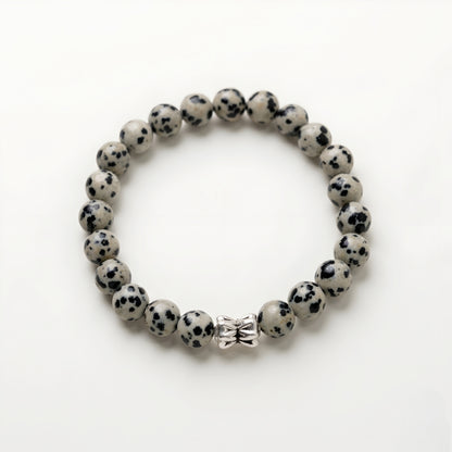 Natural Dalmatian Jasper bracelet featuring 8 mm cream and black speckled gemstone beads with a butterfly accent bead on a smooth stone background.