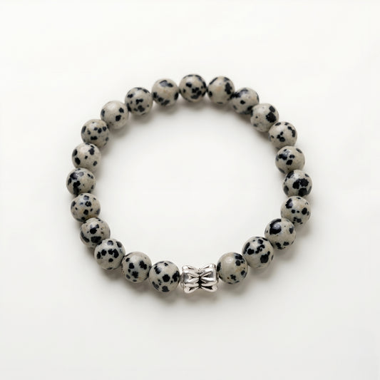 Natural Dalmatian Jasper bracelet featuring 8 mm cream and black speckled gemstone beads with a butterfly accent bead on a smooth stone background.