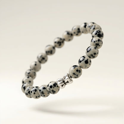 Natural Dalmatian Jasper bracelet featuring 8 mm cream and black speckled gemstone beads with a butterfly accent bead on a smooth stone background.