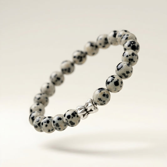 Natural Dalmatian Jasper bracelet featuring 8 mm cream and black speckled gemstone beads with a butterfly accent bead on a smooth stone background.