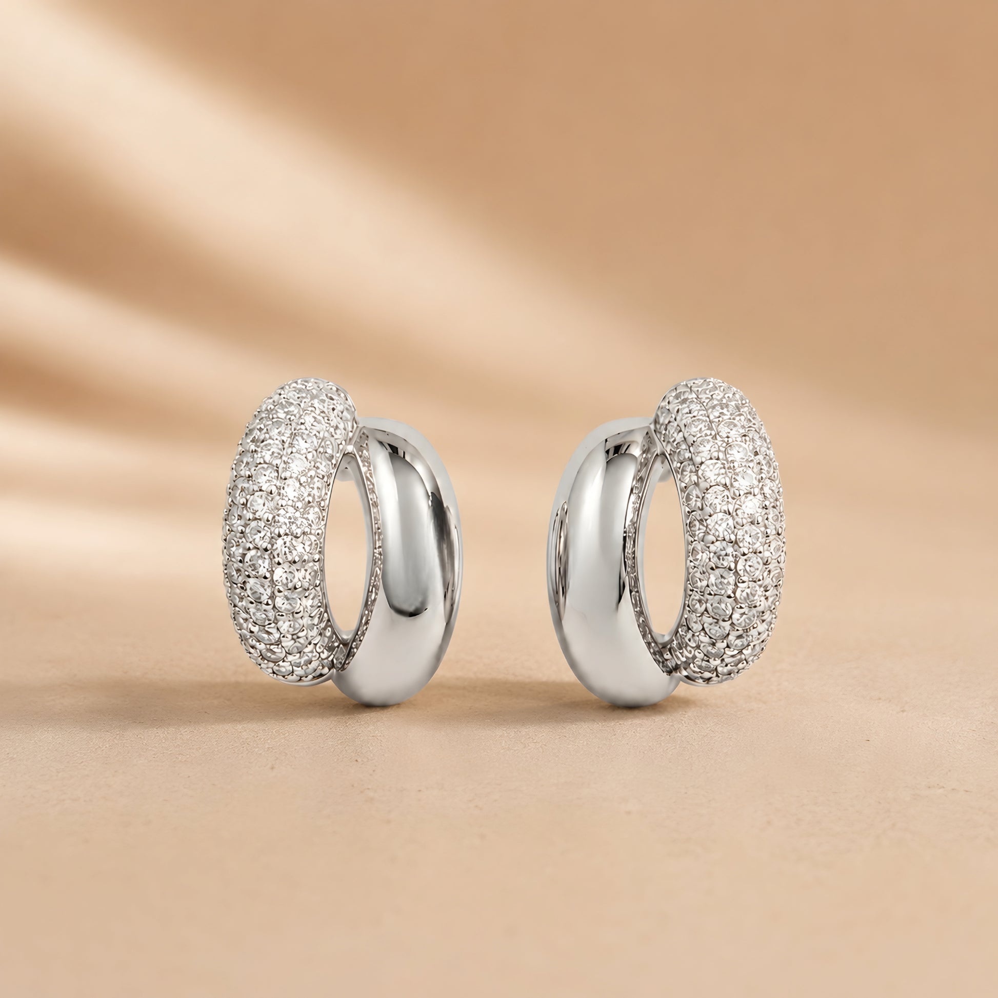 Silver toned anti tarnish pave stud earrings with dual finish and sparkling stone detailing worn on ear.