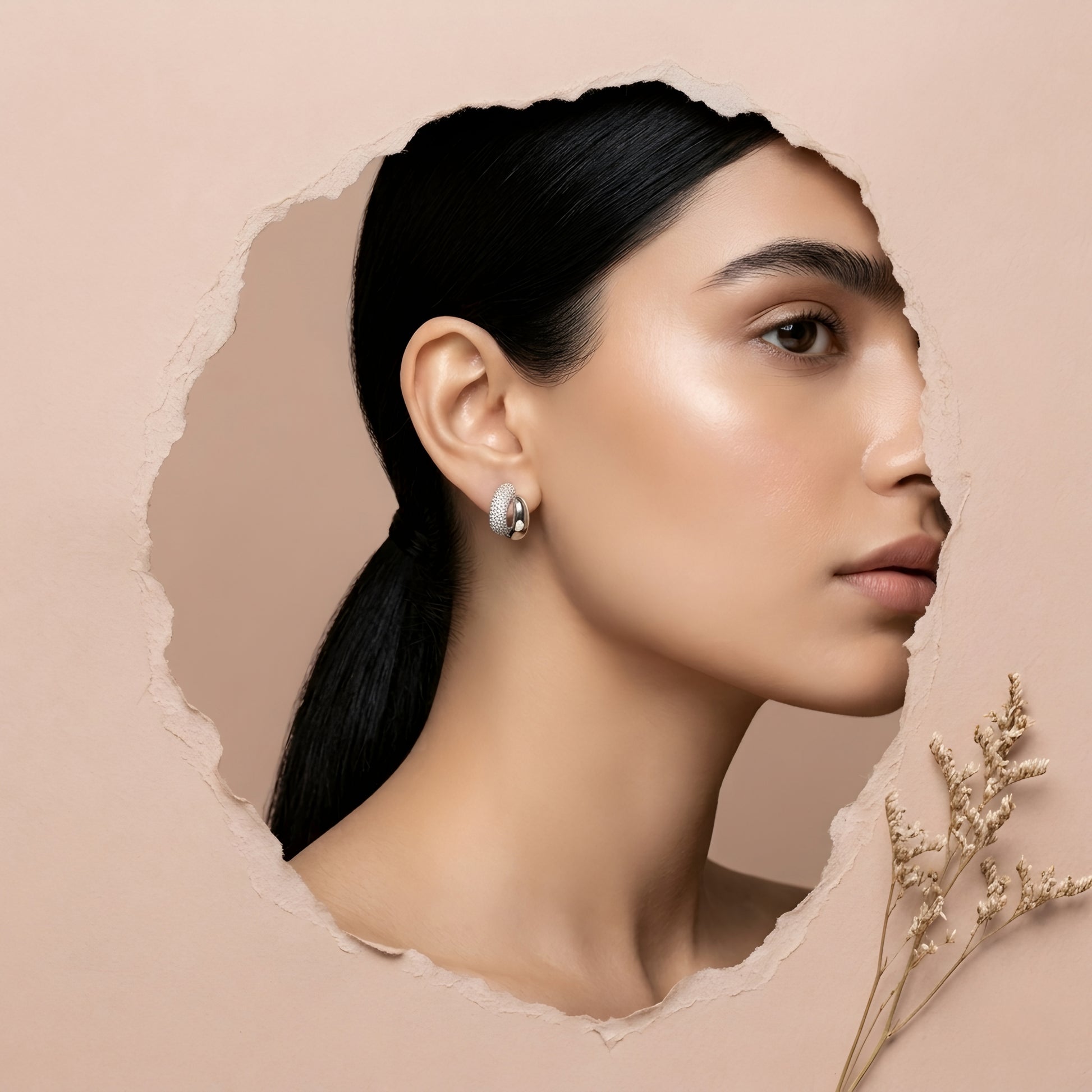 Silver toned anti tarnish pave stud earrings with dual finish and sparkling stone detailing worn on ear.