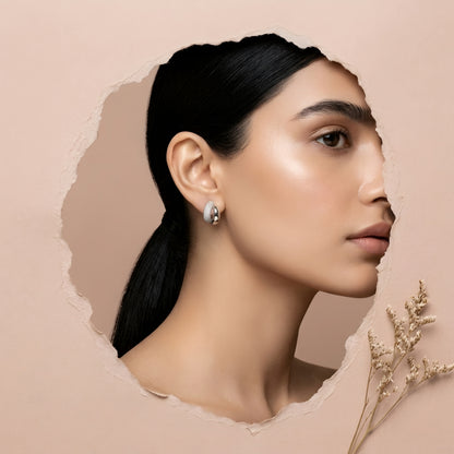 Silver toned anti tarnish pave stud earrings with dual finish and sparkling stone detailing worn on ear.