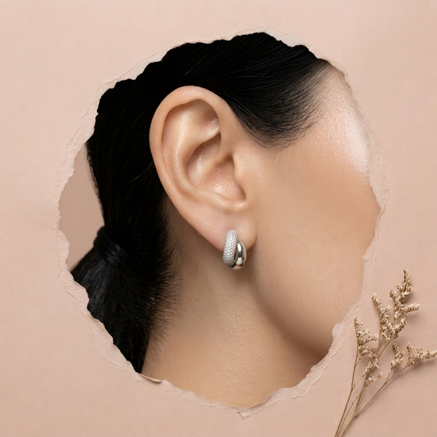 Silver toned anti tarnish pave stud earrings with dual finish and sparkling stone detailing worn on ear.