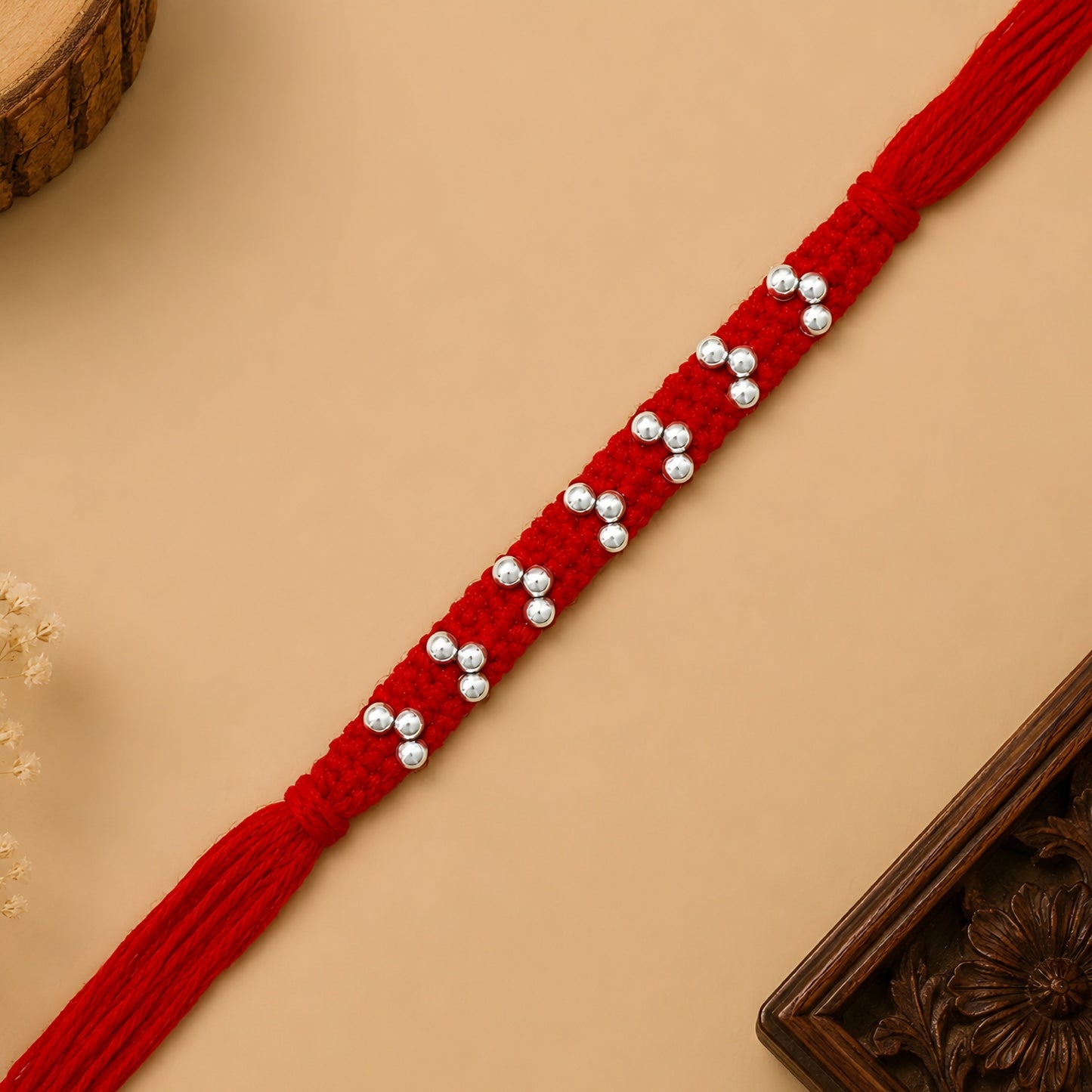 Silver handcrafted bead rakhi with polished silver beads on a braided red thread for Raksha Bandhan