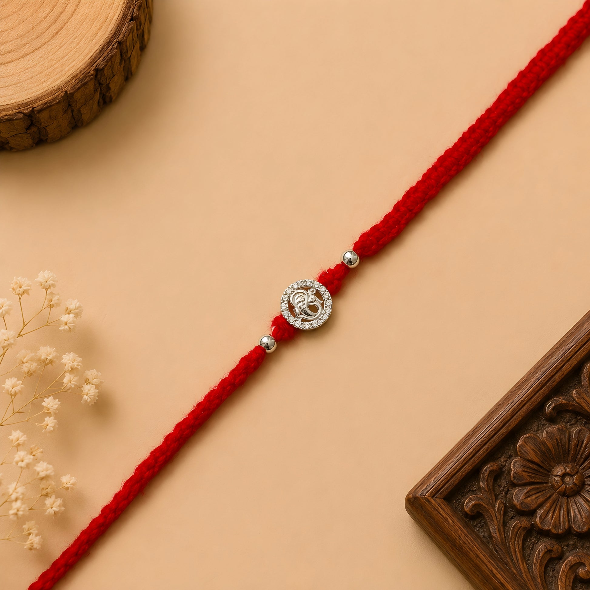 Silver Ganesh Stone Rakhi with sparkling circular design and red braided thread for Raksha Bandhan