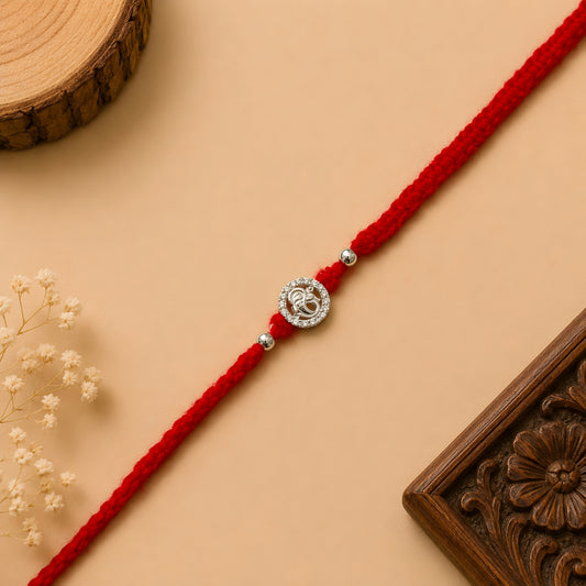 Silver Ganesh Stone Rakhi with sparkling circular design and red braided thread for Raksha Bandhan