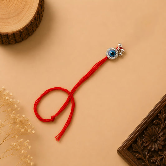Handcrafted sterling silver evil eye Bhabhi Rakhi with sparkling stone detailing, silver ghungroo charms and premium red thread