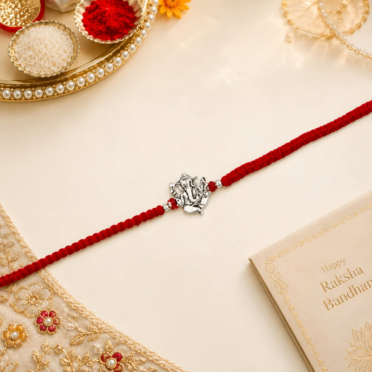 Ganesha silver Rakhi with red braided thread for brother