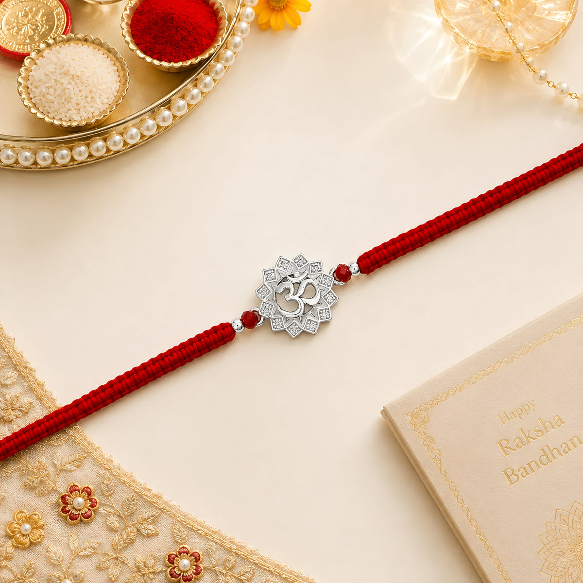 Om silver Rakhi with lotus design and red braided thread for brother