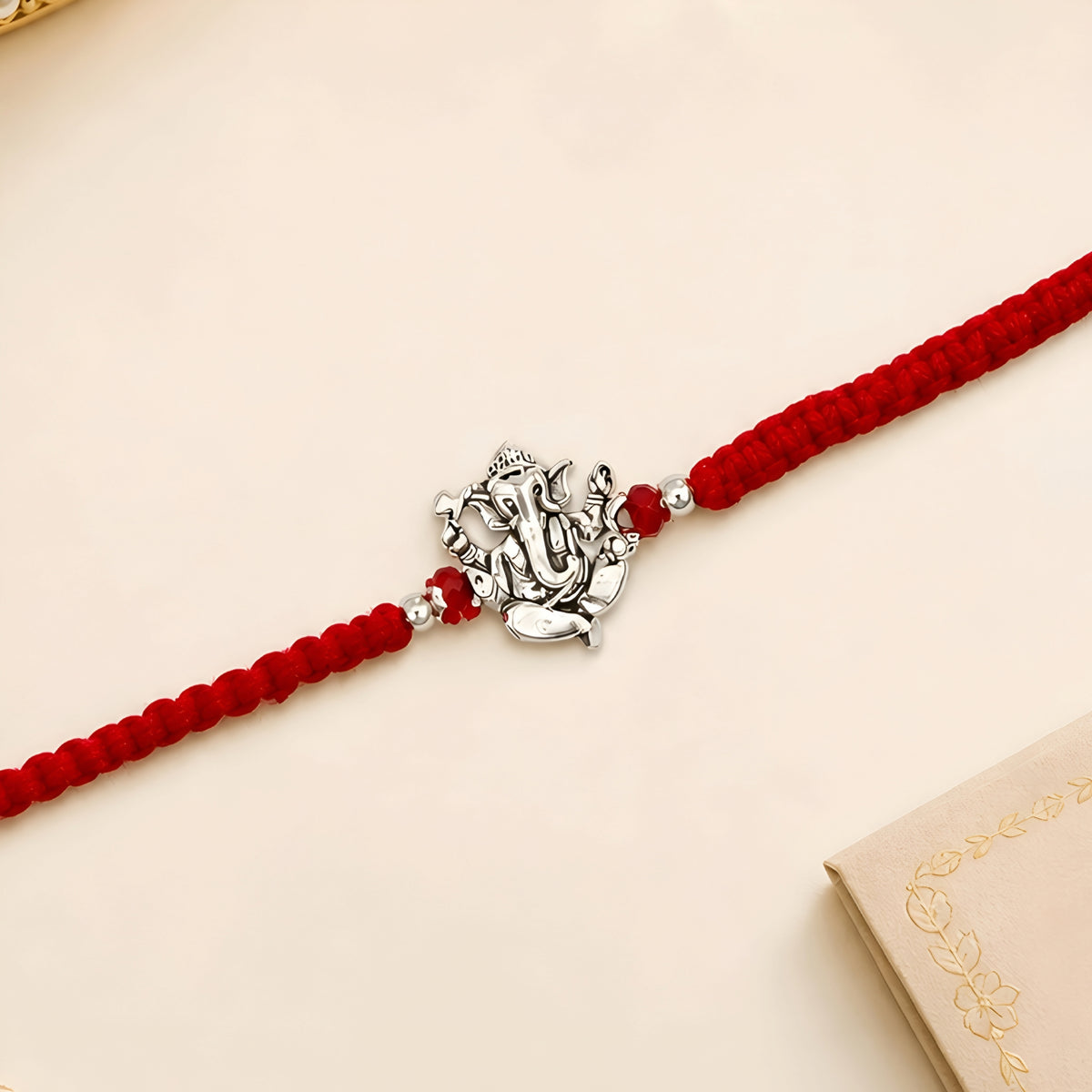 Ganesha silver Rakhi with red braided thread for brother