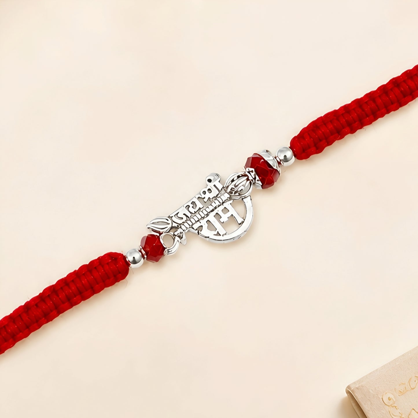 Shree Ram silver Rakhi with red braided thread and silver centerpiece