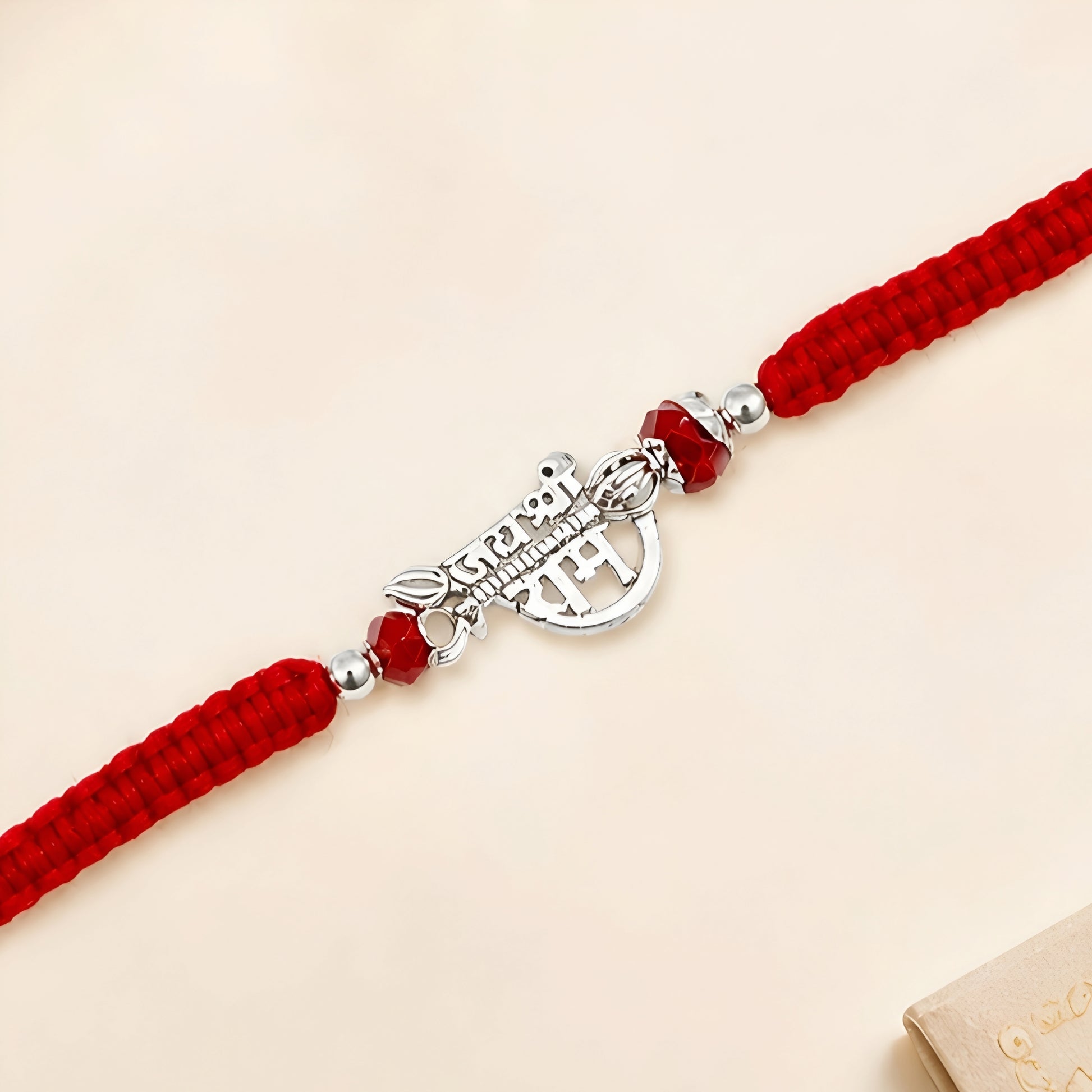 Shree Ram silver Rakhi with red braided thread and silver centerpiece