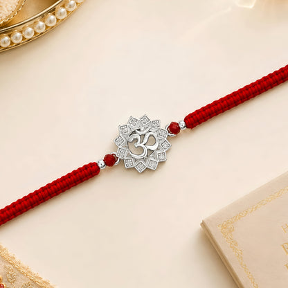 Om silver Rakhi with lotus design and red braided thread for brother
