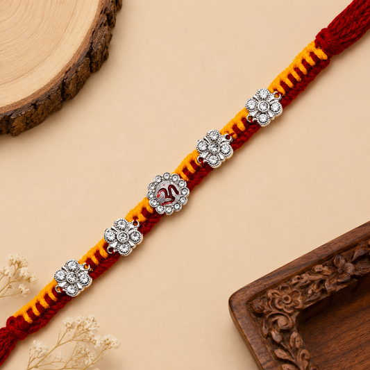 Silver Om floral stone Rakhi with sparkling flower accents and red-saffron braided thread for Raksha Bandhan