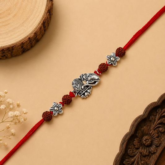 Silver Ganesh Shivling Rakhi with original Rudraksha beads, floral accents and red thread for Raksha Bandhan